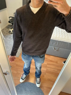 Mörkbrun Stickad Tröja Från bläck - Mörkbrun stickad tröja med V-ringning och ribbade muddar vid ärmslut och nederkant. Tröjan har en klassisk och enkel design som passar till det mesta. Perfekt för dig som gillar en stilren look. Nypris 899 mitt pris 749. Använd en gång 