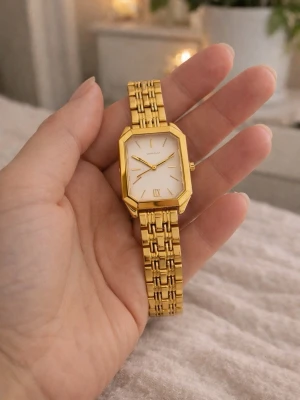 Elegant Guldfärgad klocka med vit urtavla. - Stilren guldfärgad klocka från Capwell med rektangulärt ur och vit urtavla. Klockan har en länkad metallrem och minimalistiska detaljer på urtavlan. Perfekt accessoar för dig som gillar klassisk och elegant stil.