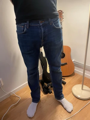 Nudie Jeans Grim Tim - Strl W31L30 i en mörkblå färg med ljusbrun stitching där bak! Sitter ganska relaxed/skinny som ni ser! Hör av er vid frågor eller funderingar, eller prisförslag! Har en lagning i skrevet men inget märkbart!