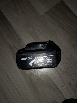 Makita 18V Li-ion batteri 3.0Ah - Makita 18V lithium-ion batteri med kapacitet på 3.0Ah. Batteriet är svart med tydlig märkning i vitt och silver. Passar till Makitas elverktyg och har robust plastkonstruktion med anslutningskontakter i metall och plast. Fungerar utmärkt!