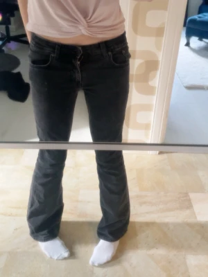 Svarta bootcut jeans med hög midja - Säljer ett par svarta bootcut jeans med hög midja och klassisk femficksmodell. Jeansen har en lätt utsvängd passform nedtill och är tillverkade i ett mjukt denimtyg. Perfekta för dig som gillar en retroinspirerad look.