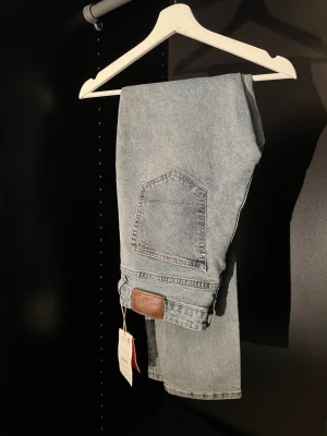 Ljusblå raka jeans från Zero Jeans - Säljer ett par ljusblå jeans från Zero Jeans med rak passform och klassisk femficksdesign. Jeansen har en snygg tvättad look och är tillverkade i bomull. Perfekta för en avslappnad och trendig stil. Aldrig använd 