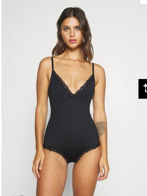 Svart spetsbody body med smala axelband shape Lindex  - Snygg svart body med smala justerbara axelband och v-ringning. Kanterna är dekorerade med fin spets både vid bysten och bensluten. Shape . Lindex . Använd en gång 