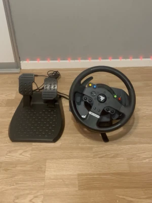 Thrustmaster Tmx ratt och pedaler USB - Funkar till Xbox och Pc Säljer en svart Thrustmaster ratt och pedalset för racing- och bilspel. Ratten har flera knappar, D-pad och är tillverkad i plast med gummigrepp. Pedalerna är också i svart plast och kopplas in via USB. Perfekt för dig som vill ta gamingupplevelsen till nästa nivå.
