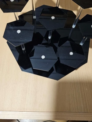 Svart hexagon hyllställ i akryl - Unikt hyllställ i svart akryl med flera hexagonformade plattor på olika nivåer, upphöjda med transparenta pelare. Perfekt för att visa upp småsaker, dekorationer eller samlarprylar på ett stilrent och modernt sätt. Materialet är blankt och ger en cool look till rummet.