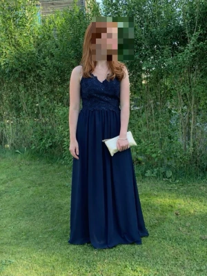 Balklänning  - Elegant mörkblå långklänning med smala axelband och vackert spetsliv. Kjolen är i ett mjukt, flytande tyg och klänningen har en djup rygg. Perfekt för bal eller festligare tillfällen. Ingen synlig logga eller märke. Pris kan diskuteras 