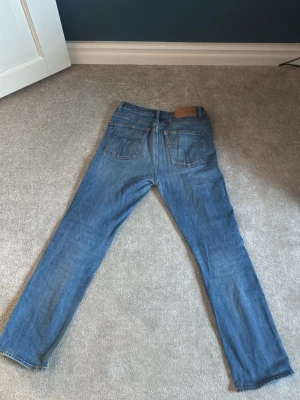 Blå raka jeans från tiger of sweden  - Klassiska blå jeans från tiger of sweden med rak passform och fem fickor. Jeansen har en ljus tvätt och är tillverkade i slitstarkt denimtyg. Perfekta för en avslappnad och tidlös stil.