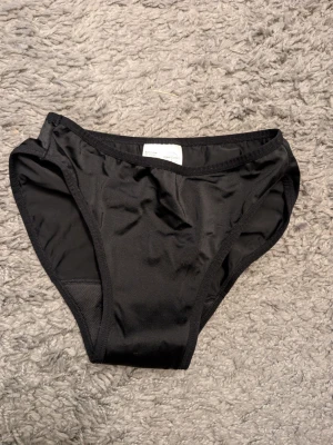 Svarta mens bikinitrosor från Comfyden Nyace - Säljer ett par svarta mens bikinitrosor från Comfydence, modell Sunshine. Trosorna har klassisk brief-passform och är tillverkade i ett mjukt och stretchigt material som känns bekvämt mot huden. Nya endast tvättade 