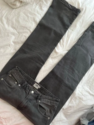 Grå bootcut Lowasit  jeans från 157 - Snygga grå bootcut jeans från 157 med klassisk femficksdesign och silverfärgade nitar. Jeansen har en rak passform med utsvängda ben och är tillverkade i mjuk denim med lite stretch för extra komfort. Slitage längst mer