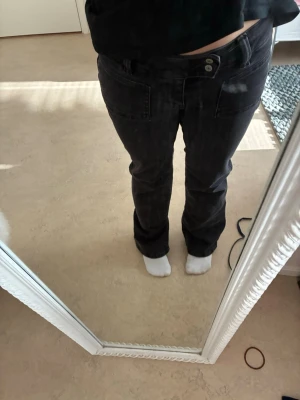 Svarta bootcut jeans från 157 - Säljer ett par svarta bootcut jeans från 157 med hög midja och dubbla knappar. Jeansen har stora framfickor och är tillverkade i stretchigt denimtyg. Perfekta för dig som gillar en avslappnad men trendig look.