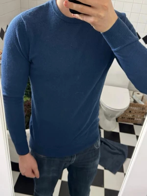 Blå kashmirtröja från John Henric - Mysig blå tröja i 100% kashmir från John Henric. Klassisk rund halsringning och långärmad modell, perfekt för dig som gillar stilren och enkel design. Supermjuk och skön att ha på sig, passar till allt och ger en clean look. Nypris ligger på cirka 2200 och jag säljer för endast 1099