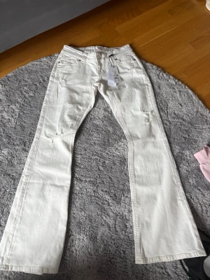 Vita low rise flare jeans M - Säljer ett par vita low rise flare jeans i storlek M. Jeansen har utsvängda ben och låg midja, perfekta för en trendig och avslappnad look. Materialet är klassisk denim och modellen är tall, vilket ger extra längd på benen.