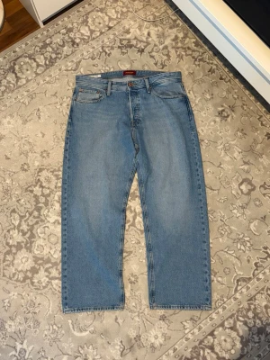 Ljusblå raka jeans från Jack & Jones - Säljer ett par klassiska ljusblå jeans från Jack & Jones med rak passform och fem fickor. Jeansen har en tidlös look med normal midja och är tillverkade i slitstark denim. Perfekta för en avslappnad och trendig stil.