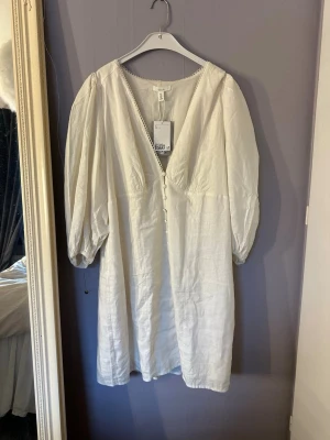 Vit klänning från H&M - superfin klänning från H&M i linnemix med v-ringning och spetskant. puffiga trekvartsärmar med resår nertill och knappar framtill. Endast testad med prislappen kvar! 💕 Helt slutsåld på hemsidan! nypris 549kr💕jag är ungefär 168cm lång och brukar ha M i vanliga fall 