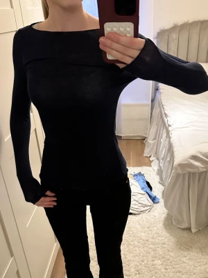 Intmissimitröja - Säljer en mörkblå, långärmad topp med tight passform. Toppen har en enkel, stilren design med rund halsringning och är gjord i ett tunt, stretchigt material som sitter snyggt på kroppen. Perfekt att styla med jeans eller kjol.