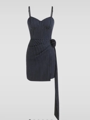 Marinblå randig kort klänning - Snygg marinblå kort klänning med vita ränder och smala axelband. Klänningen har en markerad byst, omlottkänsla med knyt i sidan och en lång detalj som hänger ner. Perfekt för dig som vill ha en trendig och unik look.