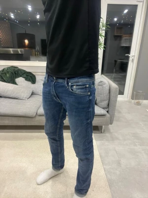 Mörkblå slim fit jeans - Säljer ett par mörkblå slim fit jeans med klassisk femficksmodell och snygga slitningar. Jeansen har normal midja och smal till rak passform. Riktigt sjysta jeans att rocka vardagligen och fin kvalitet 