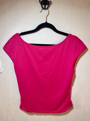 Neonrosa topp med öppen rygg - En enkel och snygg rosa topp med bred halsringning och korta ärmar. Tillverkad i mjukt bomullsmaterial som känns skönt mot huden. Perfekt att matcha med jeans eller kjol för en fräsch look. Helt ny, oanvänd. SHEIN, storlek L. Djur, rök och parfymfritt hem.