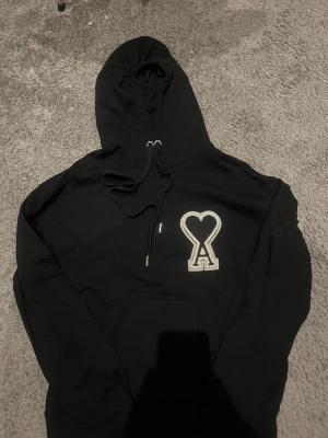 Svart Ami Paris hoodie - Säljer en svart hoodie från Ami Paris. Ny och inga märken eller defekter. Passar perfekt för dig som vill sticka ut lite extra i vardagen, samt perfekt för våren. Pris kan diskuteras vid snabbaffär. 