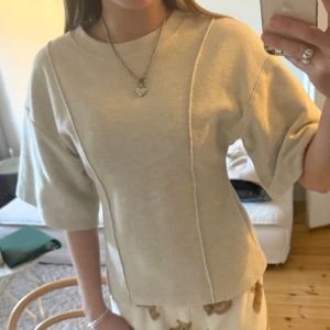 Beige croppad topp med sömdetalj - Trendig beige croppad topp med markerad söm framtill och rund halsringning. Från HM🫰