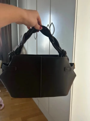 Brun  handväska med flätat handtag - Handväska från ginatricot som aldrig används. Band medföljer 