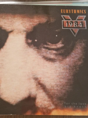 Eurythmics 1984 soundtrack LP - Soundtrack-LP till filmen 1984 av Eurythmics. Omslaget har ett stort närbildsporträtt i bruna och svarta toner, med låtlista och bilder på baksidan. Perfekt för dig som gillar klassisk synthpop och filmrelaterade samlarprylar. Inga repor.