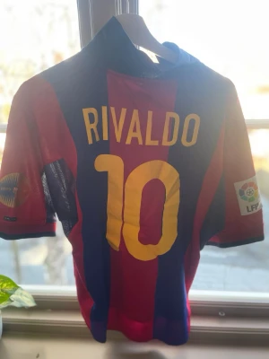 Retro Rivaldo Barcelona tröja 00/01 - En äkta barcelona tröja från säsongen 2000/2001 med rivaldo på ryggen. Tröjan säljs då jag ej använder den och har använts sparsamt sen jag köpte den. Storleken är medium i loose fit så passar både medium men också large beroende på preferens. 