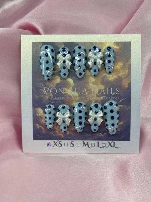 PolkaBlue (XS);Medium Almond - Handgjorda press-on naglar i en medium mandelform. Naglarna är ljusblå med mörkblå prickar och dekorerade med pärlemor vita 3D-rosetter och hjärtformade pärlor detaljer. XS: 14 mm, 11 mm, 11,5 mm, 10 mm, 8 mm 