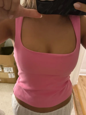 Rosa topp från Zara - Trendig rosa topp från Zara med breda axelband och fyrkantig urringning. Toppen är croppad och har en figurnära passform som framhäver siluetten. Perfekt att styla med både jeans och kjol för en cool look. Den har ett hål som man ser på tredje bilden, men det syns ej så tydligt när man har tröjan på sig.