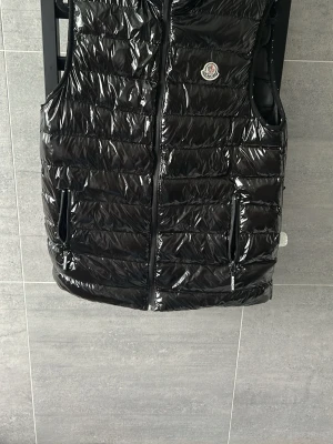 Moncler Väst  - En snygg och bekväm Moncler väst utan huva. Den har en fullt fungerande dragkedja fram. Vänsterficka är lite trasig (se på sista bilden). Säljer den pga att jag har köpt en ny väst. Storlek M