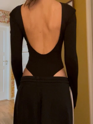 Svart långärmad body med djup rygg - Säljer denna svarta body från h&m pga dålig användning. Har klippt bort lappen men skulle säga att den är i storlek XS-XXS. Den hade axelvaddar som jag tog bort så de har ett litet hål innanför som man inte märker av. Jättebra skick❤️