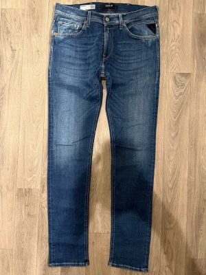 Replay Jondrill Hyperflex Jeans Blå W33/L32 - Slim Fit - Replay Jondrill Hyperflex blå jeans i stretchig Hyperflex denim med slim fit passform som sitter snyggt men lite mer rakt i benet och funkar till allt, storlek W33/L32, midja 41,5 cm, ytterbenslängd 108 cm, benöppning 16 cm, modellen är 185cm & väger 65kg, i fint skick.