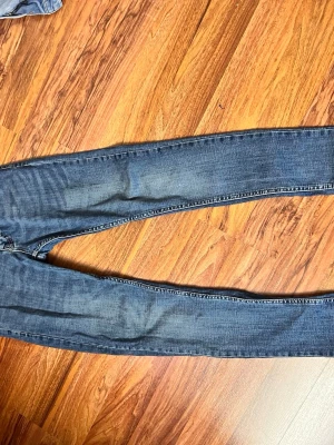 Blå slim fit jeans - Snygga blå slim fit jeans med lätt slitning och klassisk femficksdesign. Jeansen har smal passform och normal midja, perfekta för en trendig och avslappnad look. Tillverkade i denim med stretch för extra komfort.