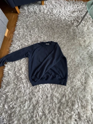 Mörkblå sweatshirt från Pier One - En stilren mörkblå sweatshirt från Pier One med rund halsringning och ribbade muddar vid ärmslut och nederkant. Perfekt för en avslappnad look och enkel att matcha med jeans eller joggers.