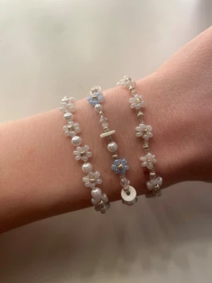 Söta pärlarmband med blommor - Tre handgjorda armband med vita och blå pärlor i blommönster. Armbanden har små vita och blå blommor, silverfärgade detaljer och karbinlås. Perfekt för dig som gillar gulliga accessoarer. Handgjorda och oanvända 🫶 10kr styck eller alla för 25kr 🫶