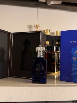 Clive Christian Addictive Arts Parfym - Lyxig parfym från Clive Christian i mörkblå glasflaska med silverdetaljer och elegant kronformad kork. Flaskan rymmer 50 ml och kommer i exklusiv förpackning. Perfekt för dig som gillar unika och exklusiva dofter.