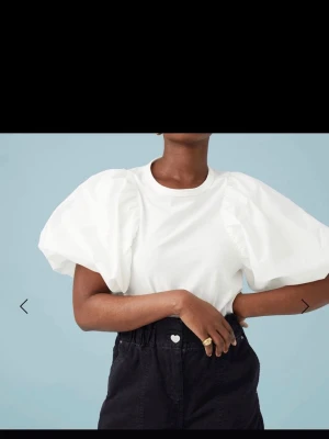 Vit topp med puffärmar från Catwalk Junkie - Trendig vit topp från Catwalk Junkie med stora puffärmar och rund halsringning. Tillverkad i 100% ekologisk bomull för en mjuk och skön känsla. Perfekt för dig som vill sticka ut med en cool och modern look. Ny med prislappen 
