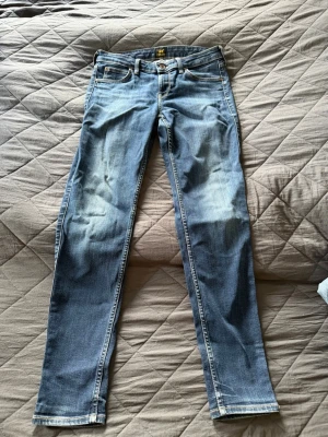 Lee jeans scarlett - Snygga blå slim fit jeans med klassisk femficksdesign. Jeansen har normalhög midja och raka ben. Tillverkade i denim med kontrastsömmar och dragkedjegylf. Perfekta för en avslappnad och trendig look. Strl 29/31