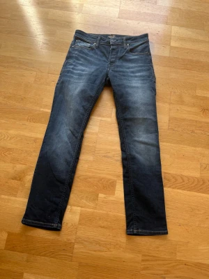 Jack&Jones jeans - Snygga mörkblå jeans från Lee med raka ben och en relaxed look. Tillverkade i bomull med en liten läderpatch bak i midjan. Perfekta för en avslappnad stil.