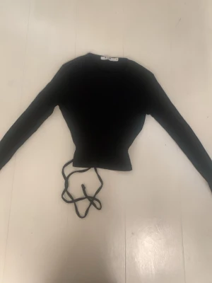 Tight långärmad tröja ribbstickad💕👌🏼 - En tight långärmad tröja som är ribbstickad. På baksidan på ryggen har den snören som man knyter och har en rosett. Den är svart.