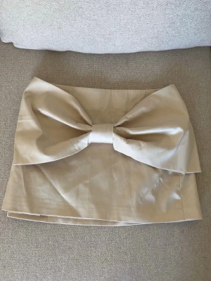 Kjol med rosett  - Beige kjol med rosett från Zara. Storlek S. Fint skick då den enbart använts 2 gånger. Nypris 299.