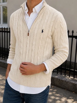 Kabelstickad tröja Polo Ralph Lauren -  Den är l men sitter som m s. Kabelstickad offwhite tröja från Polo Ralph Lauren med halv dragkedja och broderad logga på bröstet. Tröjan har hög krage och är tillverkad i mjukt material, perfekt för lager på lager. Klassisk och stilren design som funkar året runt.