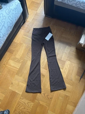 Bruna flared leggings från Lululemon - Snygga bruna leggings från Lululemon i modellen Groove Super-High-Rise Flared Pant. De har hög midja och utsvängda ben, tillverkade i det mjuka och stretchiga Nulu-materialet som känns superbekvämt. Perfekta för en trendig och avslappnad look.