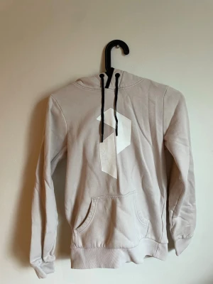 Peak performance hoodie - Snygg peak performance hoodie med stor vit geometrisk logga på bröstet och svarta dragsnören i huvan. 