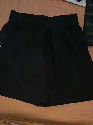Svarta  under armour shorts - Stilrena svarta shorts med hög midja och enkel design. Perfekta för en avslappnad och trendig look. Passar till många olika outfits och är lätta att matcha.