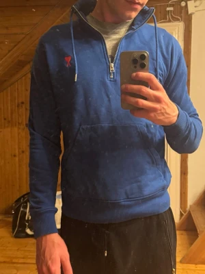 Blå zip från Ami - Ami Paris half zip med snören. Storlek S. Jag är 183 och 70 kg och den sitter lite tajt på mig. Så rekommenderas att man är lite mindre. Litet hål i armen men annars bra skick.  Inköpt på farfetch och har digitalt kvitto :)