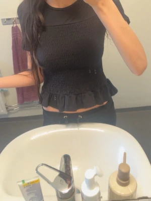 Svart croppad topp med volangkant - Jättefin ribbad tröja med volang i slutet. Den var långärmad innan men jag har klippt ärmarna och sytt upp de. Så man ser sömmen lite som jag visar på bilden, men det är inget man tänker på när man har på sig tröjan💗 storlek 146/152 passar mig som är XS. pris kan sänkas