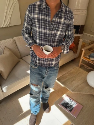 Blårutig skjorta - Snygg blårutig skjorta med vita detaljer och klassisk krage. Skjortan har långa ärmar och knäppning framtill. Perfekt för en avslappnad och trendig look. Modellen är 181cm o 73kg som referens
