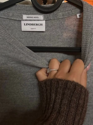 Grå merinoulltröja från Lindbergh - Snygg grå stickad tröja från Lindbergh i slim fit-modell, tillverkad i mjuk merinoull. Tröjan har V-ringning och långa ärmar, perfekt för lager på lager och enkel att matcha med olika outfits. Den är riktigt fet, sitter slim och bra. Nypris tror jag är runt 1000. Kom dm för frågor