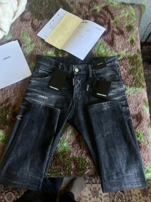  Dsquared2 jeans - Säljer ett par svarta jeans från Dsquared2 Cool guy. med coola slitningar och tvättad look. Klassisk femficksmodell med silverfärgad knapp och Dsquared2-tag vid gylfen. Jeansen är i denim och Storleken är 44 XS